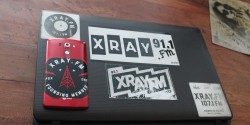 Collection of XRAY.fm stickers on laptop at community radio station. Photo: J. Waits