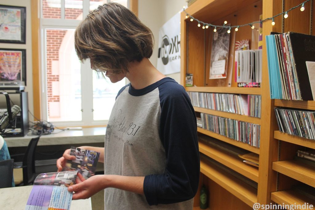 KHDX Station Manager Anna Conard flips through booklet for one of the station's compilation CDs. Photo: J. Waits