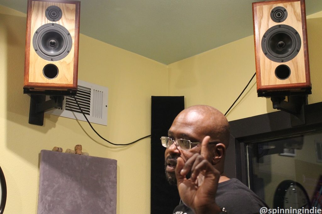 DJ Cat Daddy below the hand-crafted speakers in the KUHS-LP studio. Photo: J. Waits