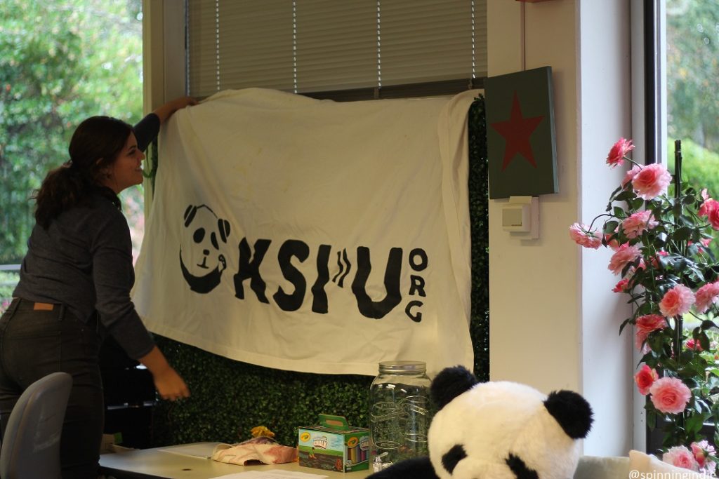 KSPU Station Manager Taylor Muñoz adjusts station banner. Photo: J. Waits/Radio Survivor