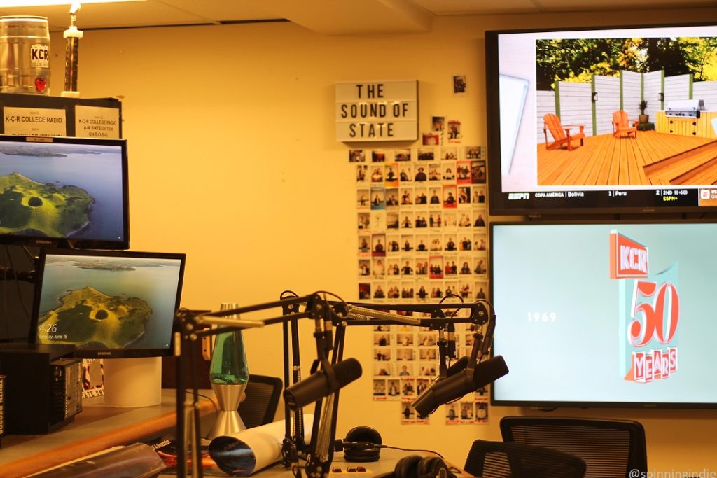 KCR College Radio studio in 2019. Pictured: computer monitors, polaroid photos on the wall, "Sound of State" sign, microphones, and "KCR 50 Years" on one of the screens. Photo: J. Waits/Radio Survivor