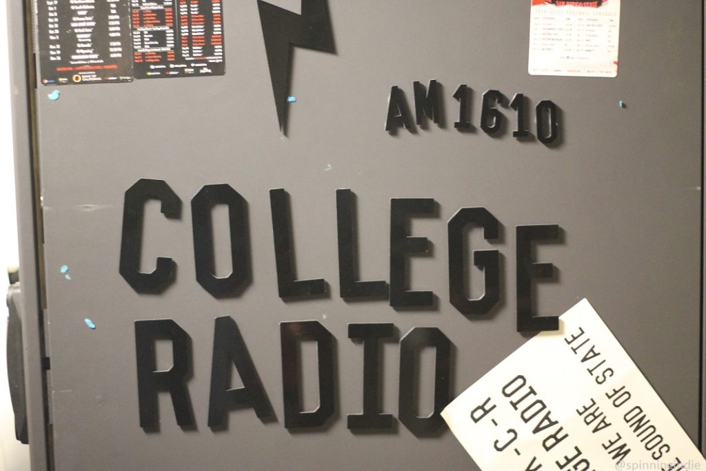 In KCR engineering room, lettering on cabinet reads: "AM 1610 college radio" and a nearby upside down sign partially reads: "we are the sound of state." Photo: J. Waits/Radio Survivor