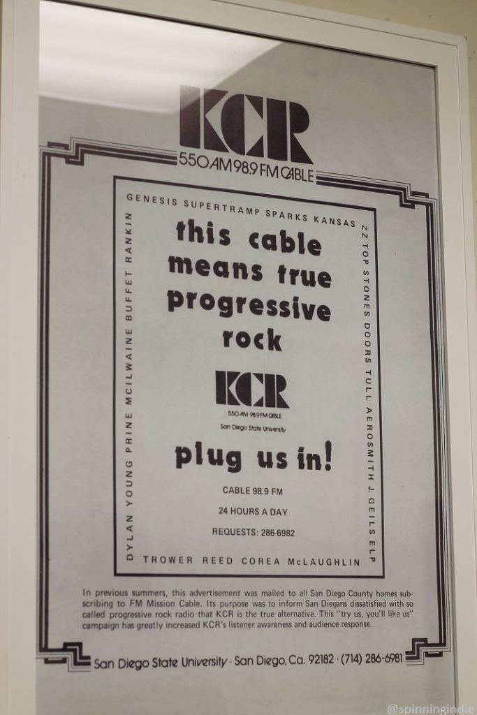 Framed vintage ad for KCR's cable signals. Copy reads in part: "this cable means true progressive rock. KCR 550 AM 98.9 FM cable. plug us in! Cable 98.9 FM 24 hours a day. requests 286-6982." Ad is framed with names of artists, including Genesis, Supertramp, Sparks, Kansas and more. Photo: J. Waits/Radio Survivor