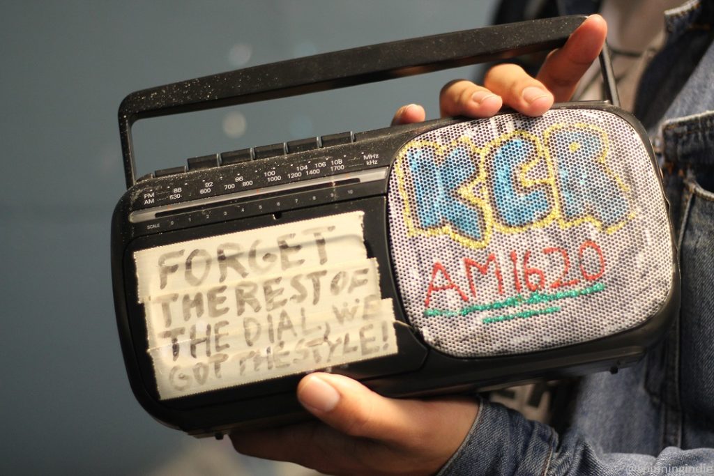 Black vintage decorated boombox, with "Forget the rest of the dial, we got the style" written on white tape and "KCR AM 1620" drawn with puffy colorful paint on the speaker. Photo: J. Waits/Radio Survivor