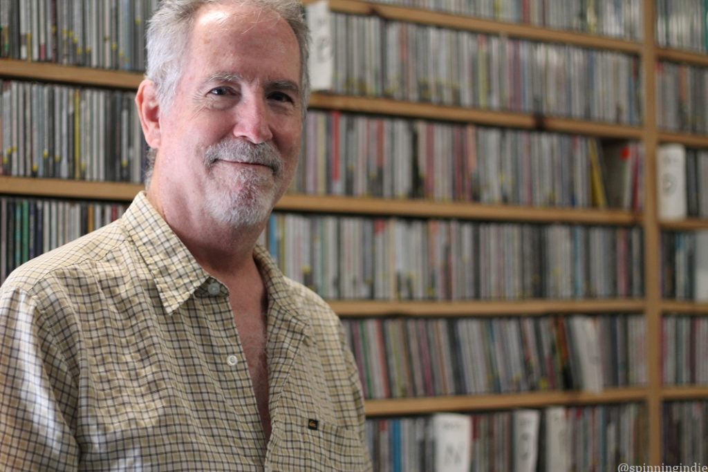 Michael Elam at Mana'o Radio, with shelves of CDs in the background. Photo: J. Waits/Radio Survivor