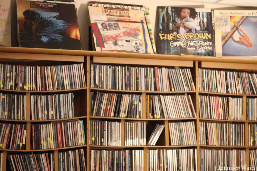 Wall of shelves of CDs, with vinyl records propped on the top shelf at college radio station WCDB. Photo: J. Waits