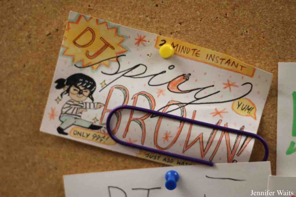 Index card posted to bulletin board at college radio station WCDB. Card has hand-drawn image of girl in pig tails. Card reads: 2 minute instant. DJ Spicy Brown. Yum! Only 99 cents. Just add water. Photo: J. Waits