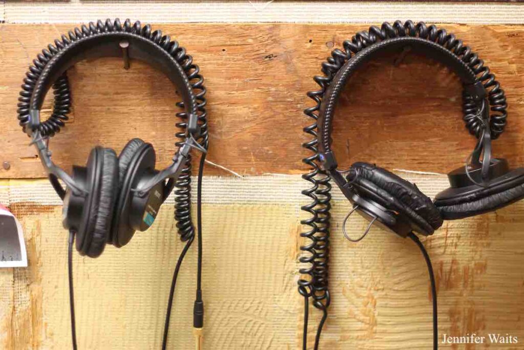Photo of two sets of black headphones hanging on nails attached to a wooden board on a wall at college radio station WRPI. Photo: J. Waits