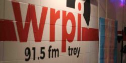 Wall mural at college radio station WRPI. WRPI in red letters. 91.5 FM Troy is below it in black letters. It's all on a white wall. Photo: J. Waits