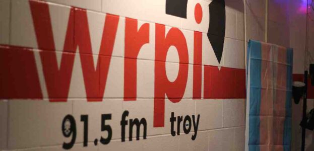 Wall mural at college radio station WRPI. WRPI in red letters. 91.5 FM Troy is below it in black letters. It's all on a white wall. Photo: J. Waits