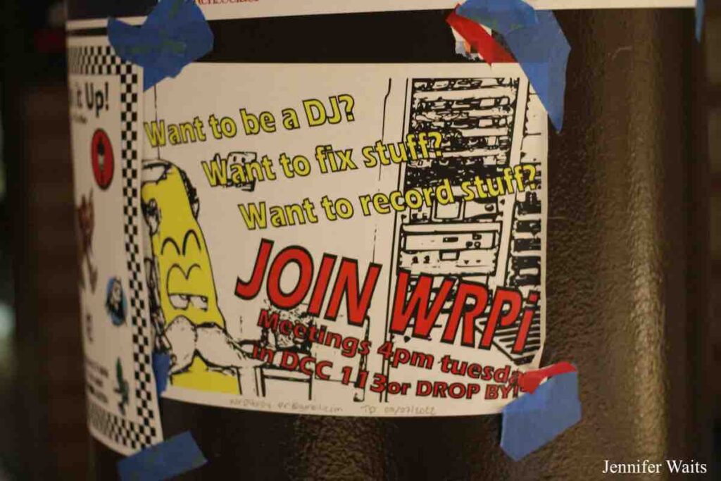 Flyer posted at WRPI that reads: "Want to be a DJ? Want to fix stuff? Want to record stuff? Join WRPI. Meetings 4pm tuesday in DCC 113 or DROP BY!" Flyer has drawing of yellow character with white mustache and another drawing of a rack of audio equipment. Photo: J. Waits