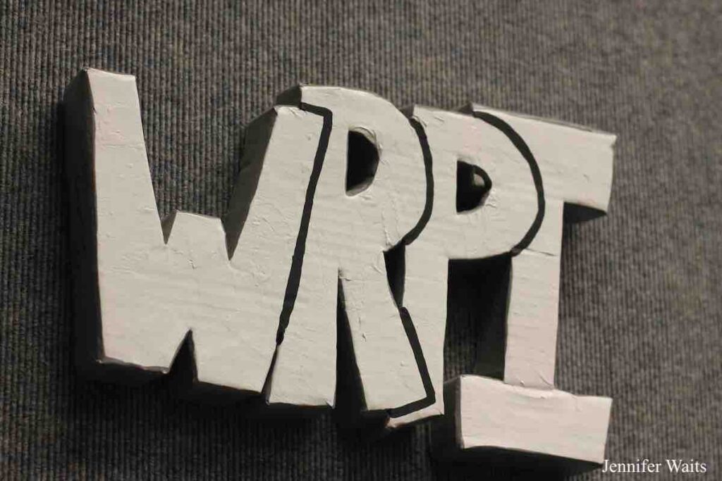 Image of 3 dimensional sign that says WRPI in block letters. It's hanging on a grey carpeted wall. Photo: J. Waits