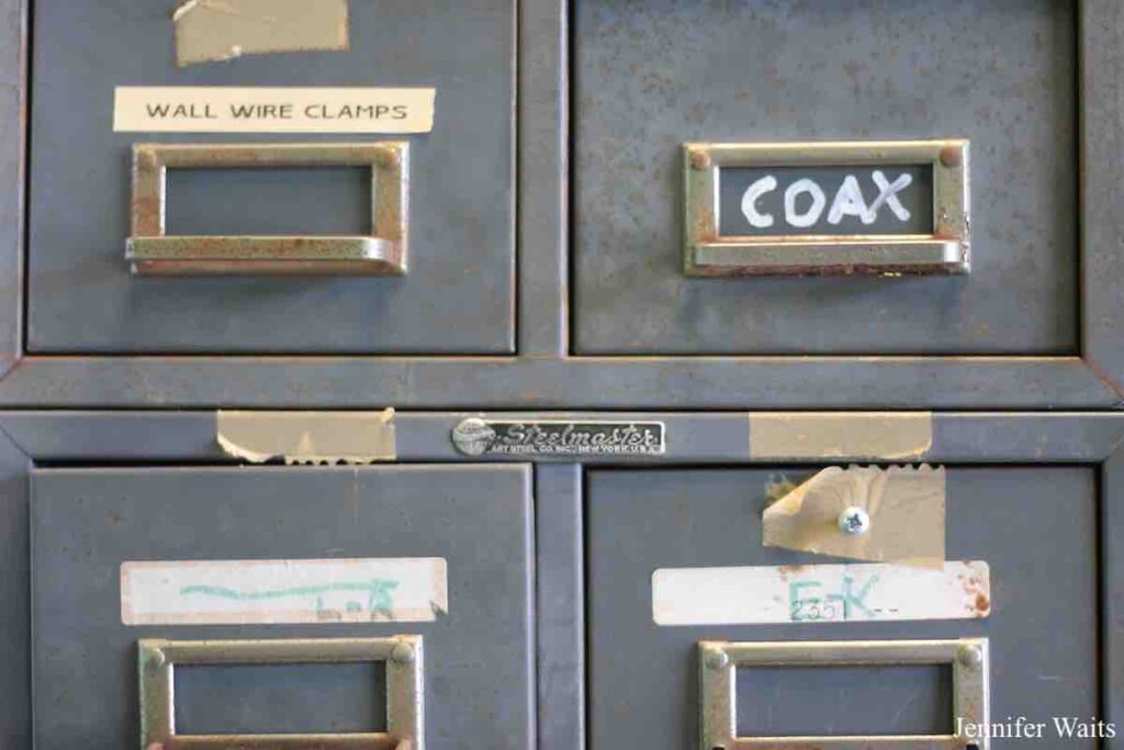 Photo of small grey metal storage drawers at college radio station WRUC labeled "wall wire clamps," "coax." Photo: J. Waits