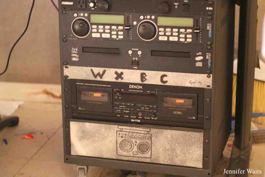 Photo of rack of audio equipment at college radio station WXBC. Two side by side CD players and a double cassette deck. Photo: J. Waits