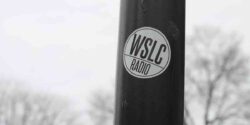 Photo of pole with white round college radio sticker on it that says WSLC Radio. Photo: J. Waits