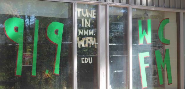 Photo of the outside of Williams College radio station WCFM. Large green writing on the station window reads "91.9 WCFM" and "tune in www.WCFM edu." Photo by J. Waits