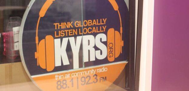 Photo of KYRS logo on the window of the community radio station. Logo reads: Think globally, listen locally KYRS" Photo by J. Waits