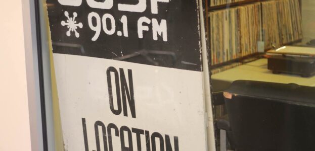 Radio Station Visit #194: CJSF-FM at Simon Fraser University Photo of window entrance to campus and community radio station CJSF. Sign in window reads "CJSF 90.1 FM On Location" and one can see record albums in station in the background. Photo: J. Waits
