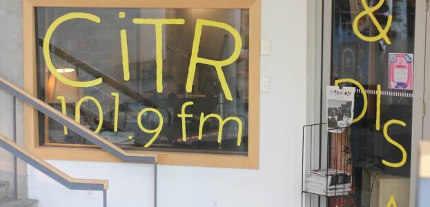 Photo of front of campus and community radio station CiTR. Pictured is the station's front window which has the letters "C-I-T-R" and "101.9 fm" written in yellow on the station's stdio window. Photo by J. Waits